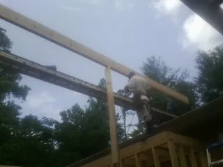 Carpenter setting a ridge beam over a new addition frame — Ice Dam Removal by Roofing Brothers in Joffre