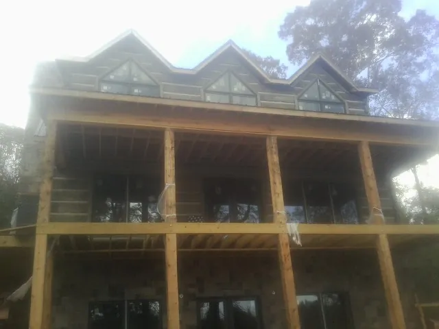 Dormers and porch framing on a large log home under construction — Roof Coating work by our crew in Joffre