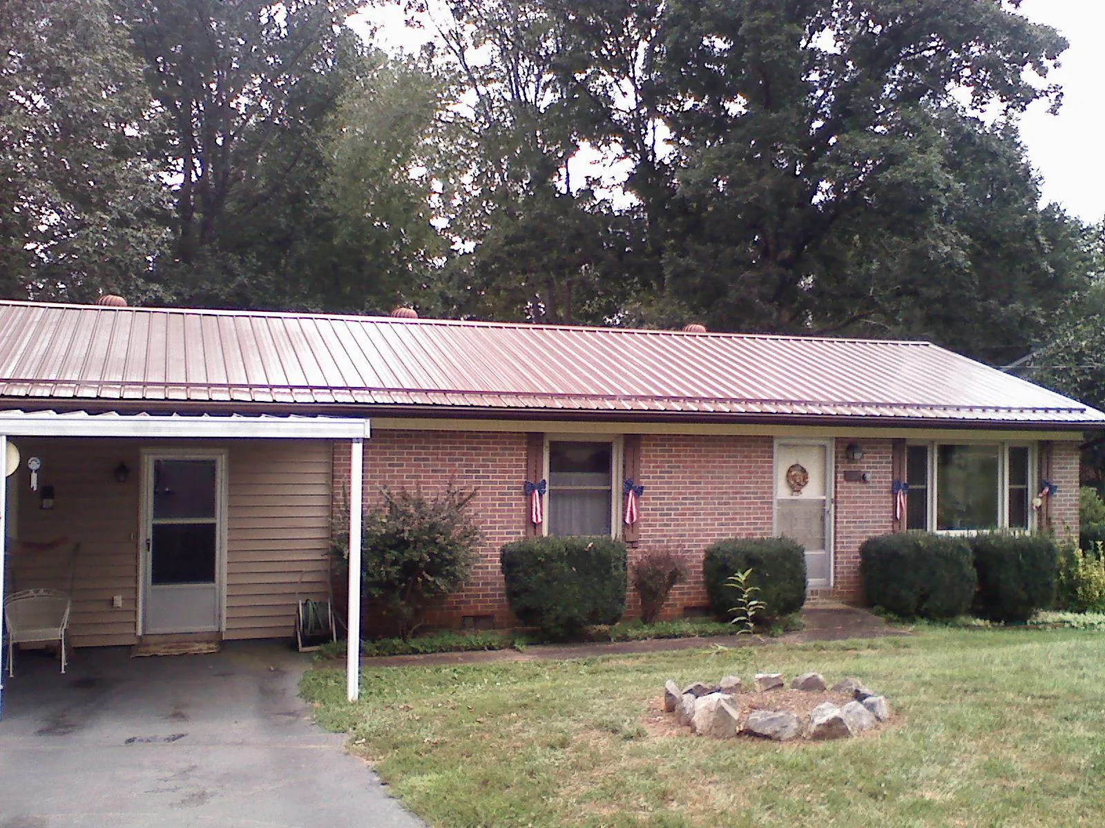 Bronze metal roof and carport on a brick ranch home — Roof Repair work by our crew in Joffre