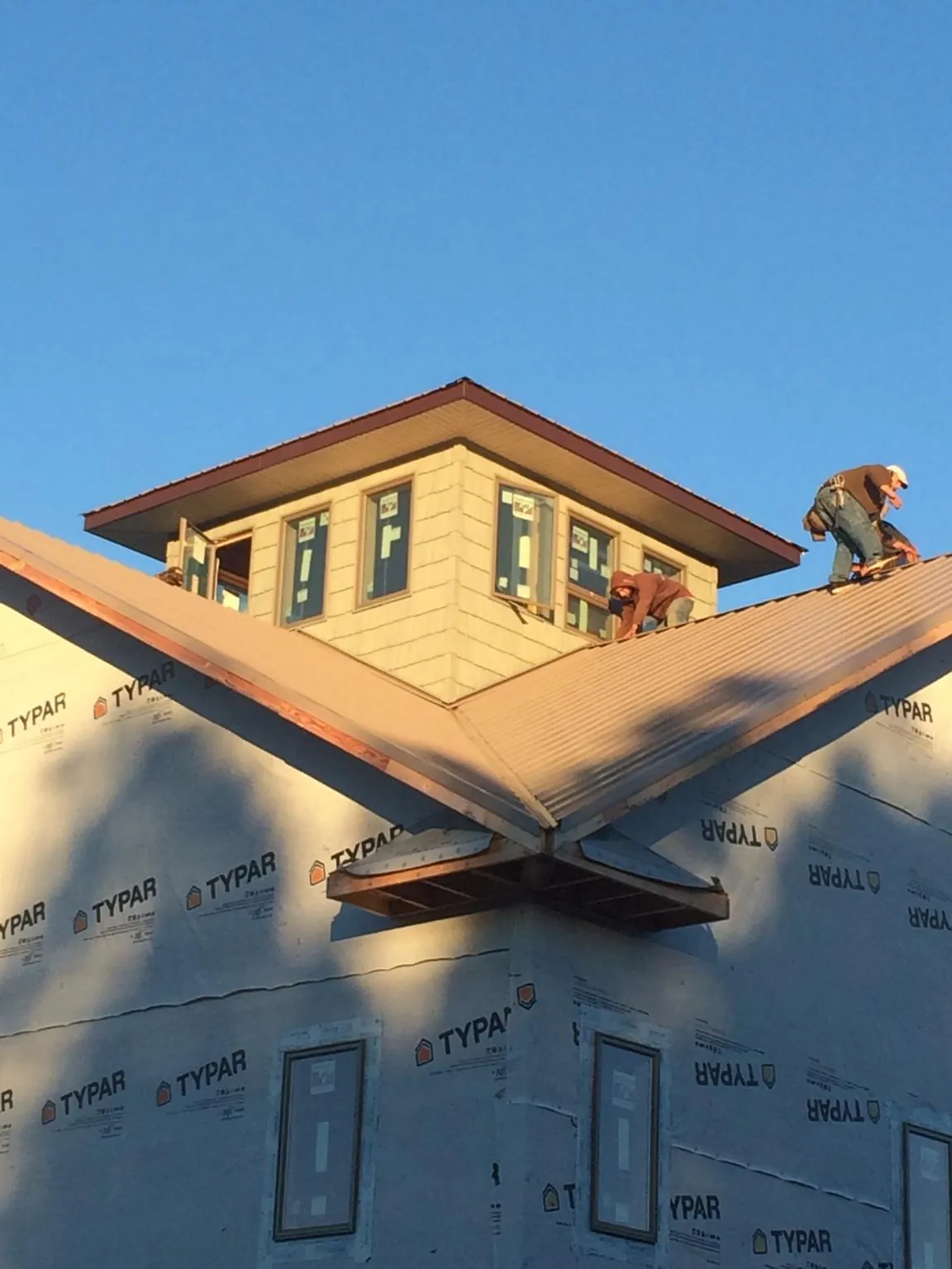 Roofers working around a rooftop cupola on a new metal roof at sunset — Roof Waterproofing in Joffre by Roofing Brothers